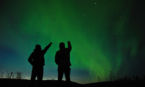 two individuals looking at the aurora borealis