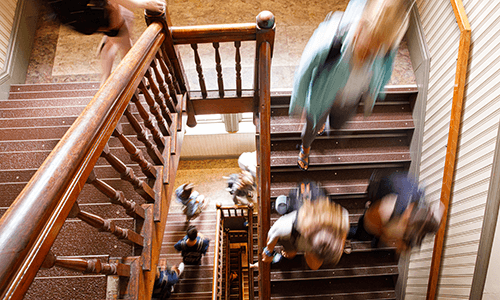 students walking down staircase in alumni hall