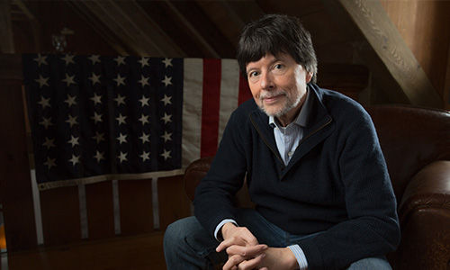 Ken Burns sits in front of an American flag