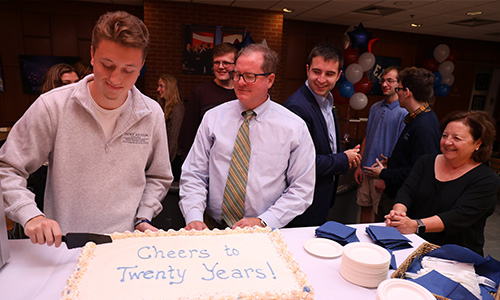 student cuts cake at the NHIOP