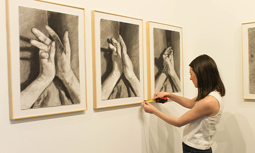student adjusts art pieces in a gallery