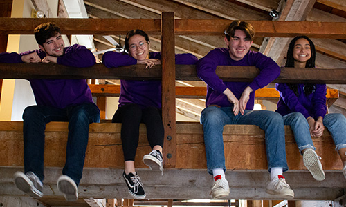 students hang off an indoor railing