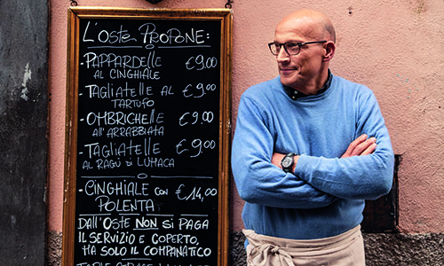 smiling man outside of a bakery wearing an apron
