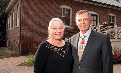 an older couple stands in front of a building on campus
