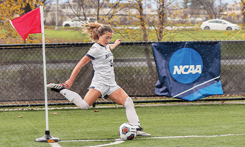 women's soccer player kicks ball on field