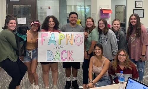 Meelia students smile with a sign that reads "FAPNO is back"