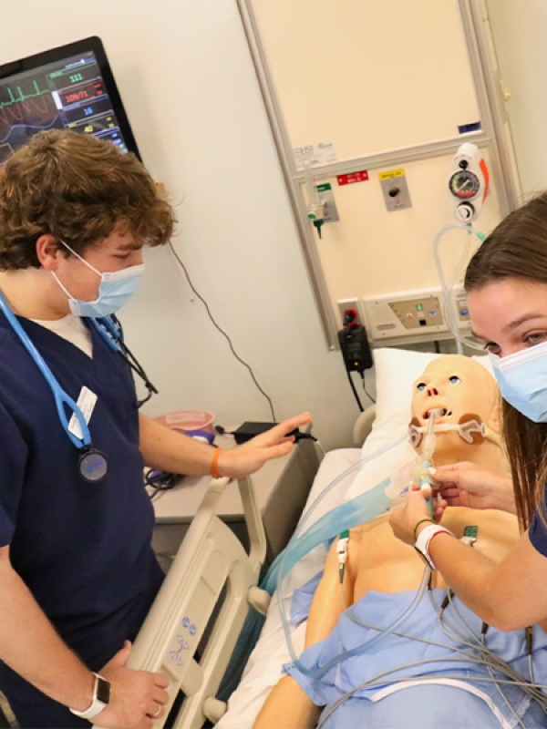two nursing students practice on a dummy