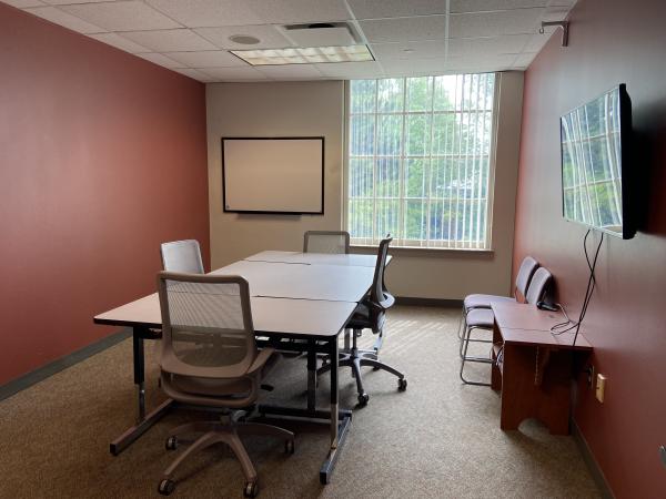 Study Room 4 with large table, 6 chairs, large monitor, whiteboard, and window