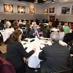 people sit at tables in the NHIOP event space