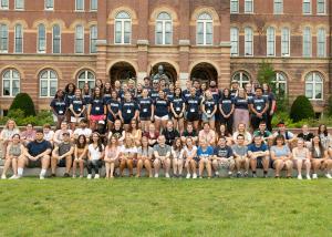 Group of students smiling at the camera in front of Alumni Hall