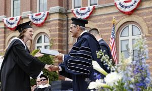 President Favazza shakes hands with a student at graduation