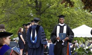 Student walks across stage with his diploma