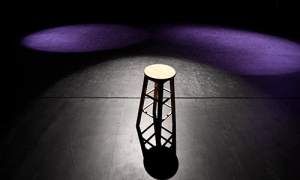 A stool in the center of a lit stage