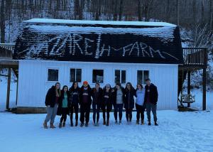 Students stand outside in front of a snow-covered barn