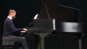 A Saint Anselm professor playing piano on stage.