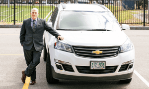 Rob Browne '95 stands by the white Chevy Traverse, nicknamed the Covid Car, used to relocate students to isolation.