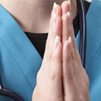 Hands of a nurse folded in prayer