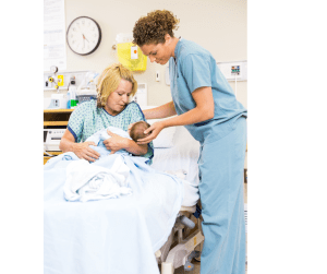 Mother holding her newborn while a nurse assists