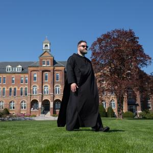 Fr. Francis McCarty, O.S.B. ’10 walks by Alumni Hall during one of the first warmer days of spring.