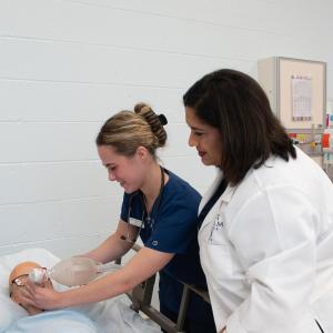 Student nurses practicing a simulation lab under the watch of their instructor