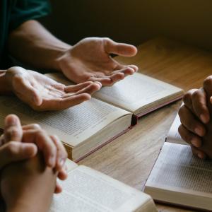 Hands praying over holy text