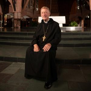 Abbot Mark Cooper, O.S.B. ’71 sitting on the altar steps in the Abbey Church