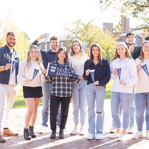 Students holding blue banners that say "Saint Anselm"