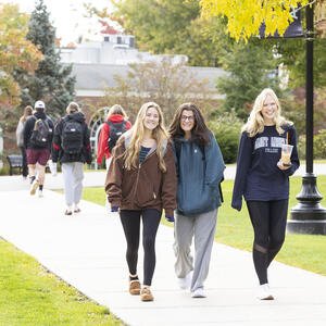 Three female students walking on a college campus.