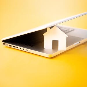 house icon in a laptop with a yellow background