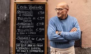 A man stands next to a cafe menu outside