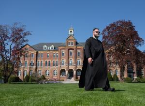 Fr. Francis McCarty, O.S.B. ’10 walks by Alumni Hall during one of the first warmer days of spring.
