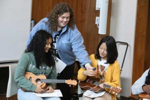 Student showing younger children how to play the ukelele
