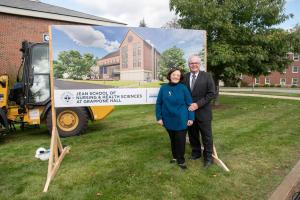 Roger and Francine Jean in front of a sign for the new nursing building