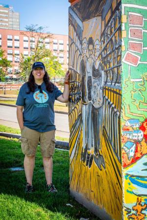 Jyl Dittbenner ’97 standing next to one of her murals