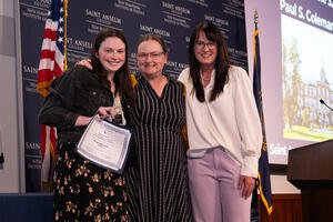 Megan Wozniak smiles holding award alongside presenters.