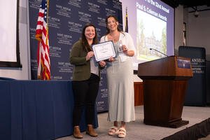 Josephine Rizzo smiles holding her award as she stands next to her presenter.