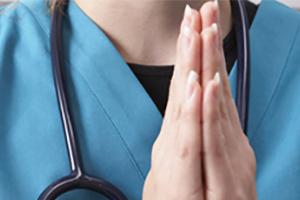 Hands of a nurse folded in prayer
