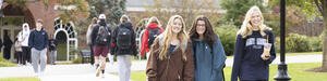 Three female students walking on a college campus.