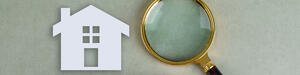 A conceptual search photo for real estate showing a wooden blocks, a paper home icon, and a magnifying glass