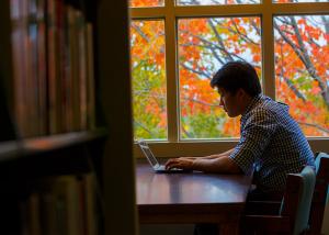 student on a laptop near the windows in the library