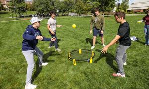 Student play spike ball on the quad