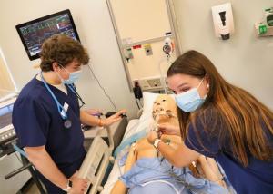 Two nursing students practice on a dummy