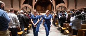 Student nurses walk down the center of the Abbey Church