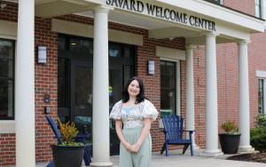 Jill Dorazio '24 standing and smiling in front of the Savard Welcome Center