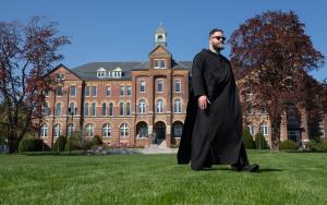 Fr. Francis McCarty, O.S.B. ’10 walks by Alumni Hall during one of the first warmer days of spring.