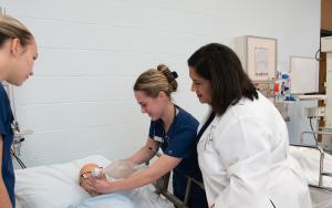 Student nurses practicing a simulation lab under the watch of their instructor