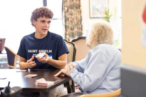 Student playing cards with an elderly woman