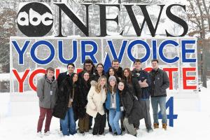 Student ambassadors standing in front of ABC's logo on campus