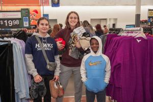 Students and a child buying items for the Christmas tree drive
