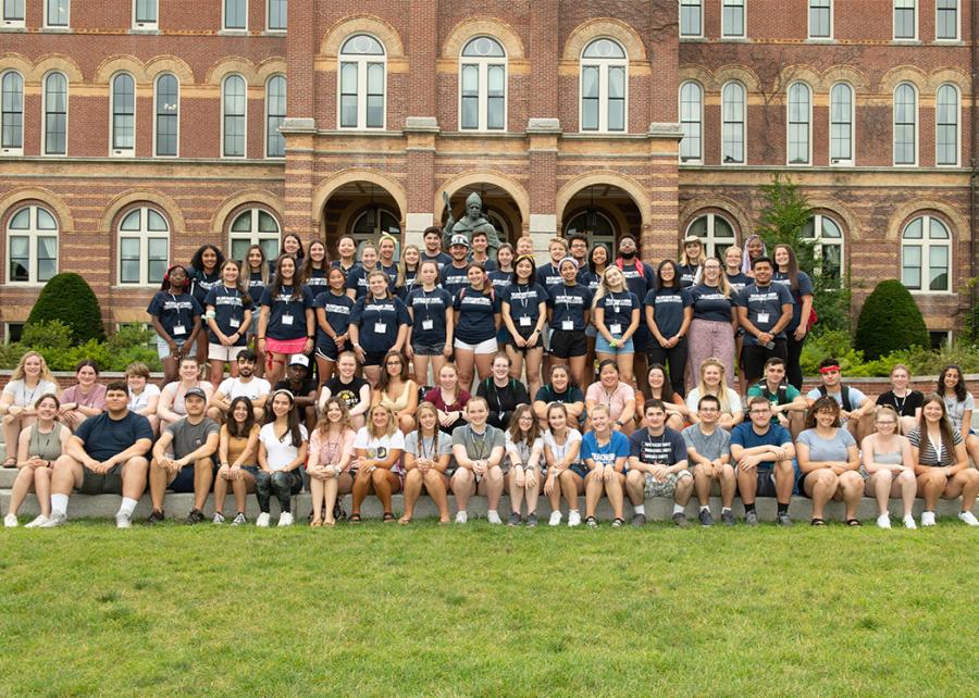 Group of students smiling at the camera in front of Alumni Hall